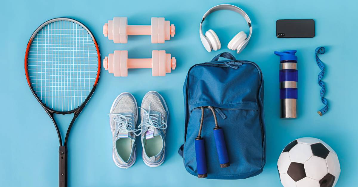  Sports-related items, including a tennis racket, soccer ball, dumbbells, and a water bottle, organized on a blue surface.